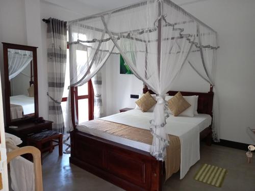 阿杭格默The Mango House Ahangama的一间卧室配有天蓬床和镜子