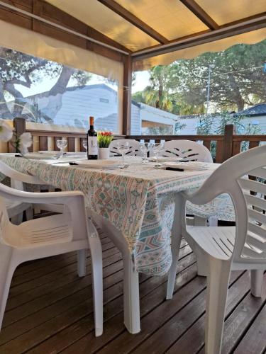 鲁西隆地区卡内Mobile home Chic的一张桌子和椅子,甲板上提供一瓶葡萄酒
