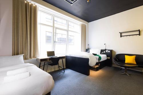 都柏林REZz Dublin的酒店客房设有两张床、一张书桌和一个窗户。