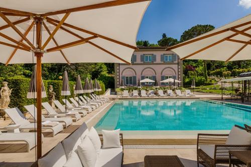 佛罗伦萨科拉别墅酒店的一个带白色躺椅和遮阳伞的游泳池