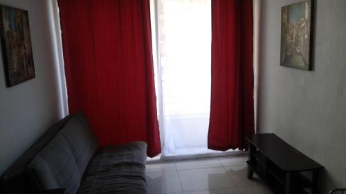 圣地亚哥DESCANSO DEL VIAJERO 2的一间配有沙发和红色窗帘的窗户的客房