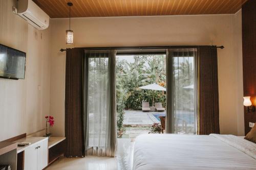 珀尼达岛Sawit Garden Cottages的一间卧室设有一张床和一个滑动玻璃门