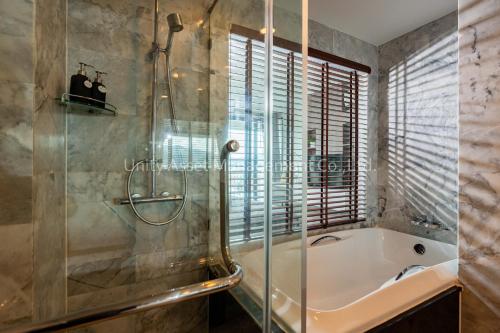 芭东海滩The Unity and The Bliss Patong Residence的带浴缸和玻璃淋浴间的浴室。