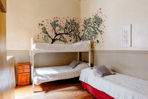 布宜诺斯艾利斯Dante y compañia的卧室配有两张双层床,墙上挂着一幅树壁画