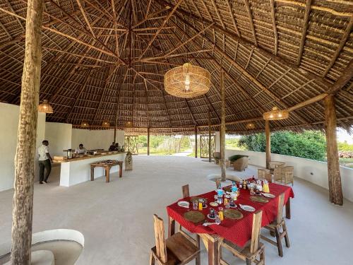 RobandaKuoom Serengeti的一间带桌子和稻草屋顶的用餐室