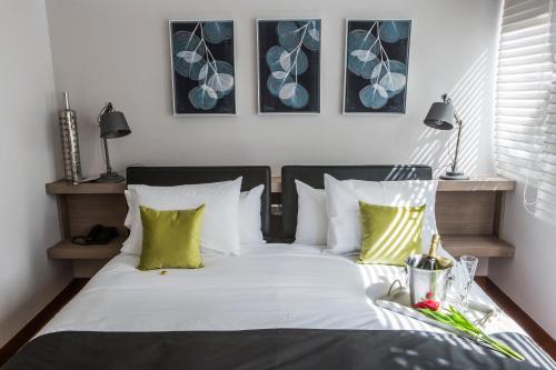 圣地亚哥Hotel Pasko的一间卧室配有带白色床单和绿色枕头的床。