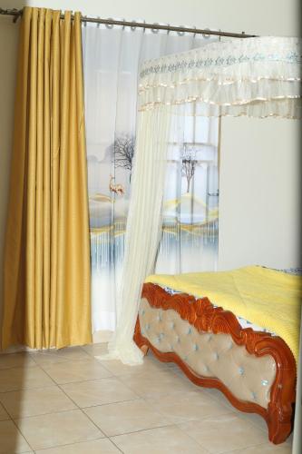 坎帕拉pettan Appartment的一间卧室设有天蓬床和黄色窗帘