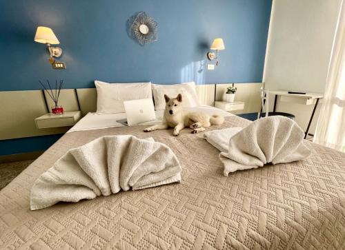 里米尼Hotel Alfa ALL INCLUSIVE 2024的一只狗躺在床上,床上有笔记本电脑