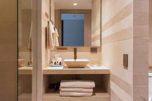 圣安德烈斯Nattivo Collection Hotel的浴室配有盥洗盆、镜子和毛巾