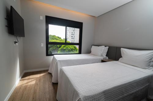 圣保罗EZ Moema Hotel的带窗户的客房内的两张床