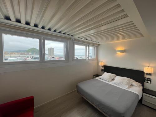 圣塞瓦斯蒂安Hotel Punta Monpas的一间卧室设有一张床和两个窗户。
