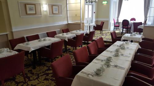 GrouvilleMaison Gorey Hotel的用餐室配有白色的桌子和红色的椅子