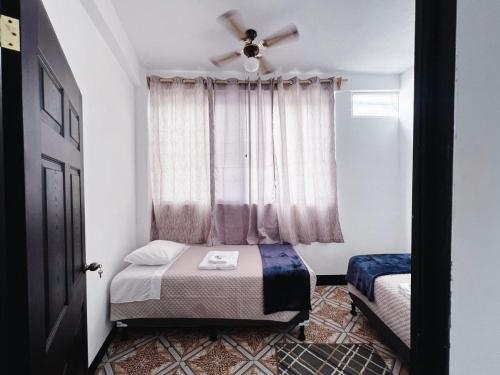 圣佩德罗拉拉古纳Apartamento en la zona viva con parqueo exclusivo的一间卧室配有一张床和一个带风扇的窗户。