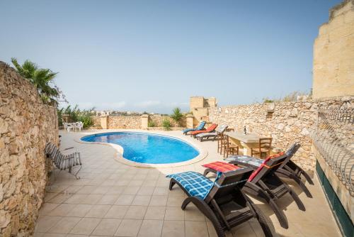 纳杜尔3 Bedroom Farmhouse with Private Pool & Views in Nadur Gozo的庭院设有游泳池、椅子和桌子。