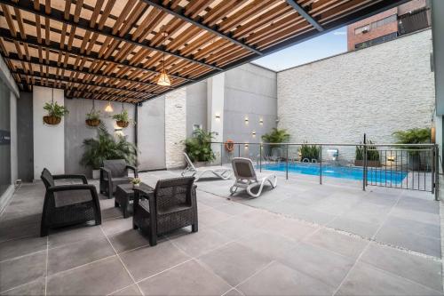 卡利Azor Hotel Cali Versalles的一个带桌椅的庭院和一个游泳池
