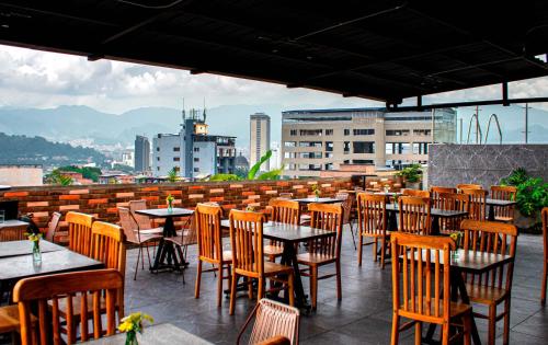麦德林Apartahotel Medellin的屋顶餐厅,配有桌椅