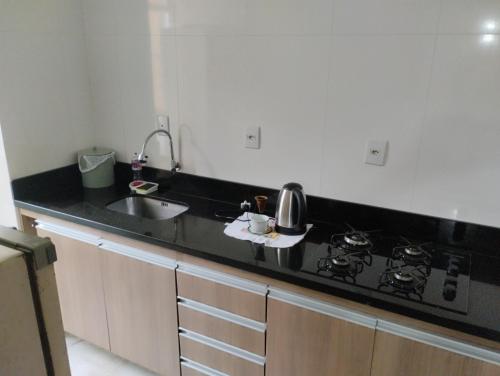 佩洛塔斯Apartamento 2 quartos的厨房配有黑色台面和水槽