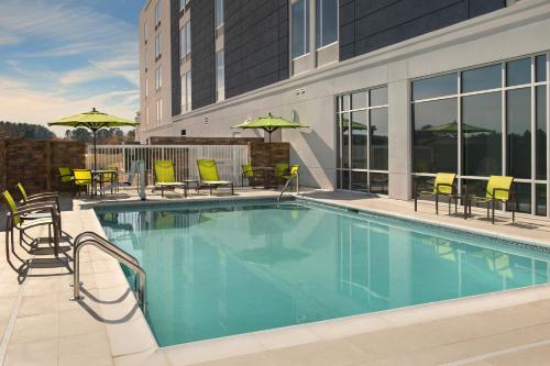费耶特维尔SpringHill Suites by Marriott Fayetteville I-95的游泳池,带椅子和遮阳伞