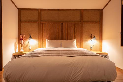热海AMAO VILLA 熱海的一间卧室配有一张带两盏灯的大型白色床。