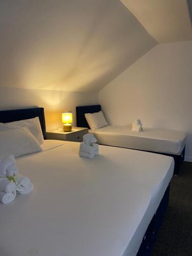 滨海韦斯顿Abbie Lodge Guest House的配有灯的房间,设有两张白色的床
