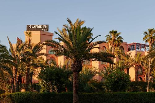 马拉喀什美丽典费斯酒店的一座楼前有棕榈树的酒店
