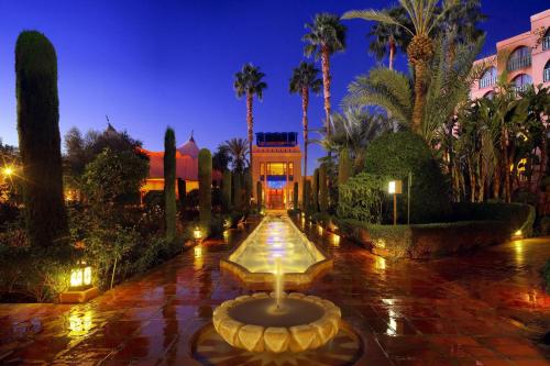 马拉喀什美丽典费斯酒店的棕榈树庭院中间的喷泉