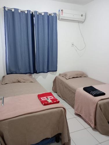圣若泽-迪里巴马尔Apartamento 1 km da praia do aracagir confortavel的配有蓝色窗帘的客房内的两张床