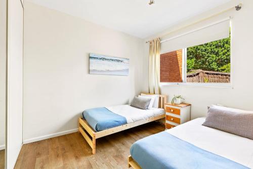 悉尼'Kangaroo Corner' Coastal Charm & Midcentury Flair的一间卧室设有两张床和窗户。