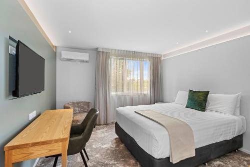 基督城Hotel Elms Christchurch, Ascend Hotel Collection的一间卧室配有一张床、一张书桌和一台电视