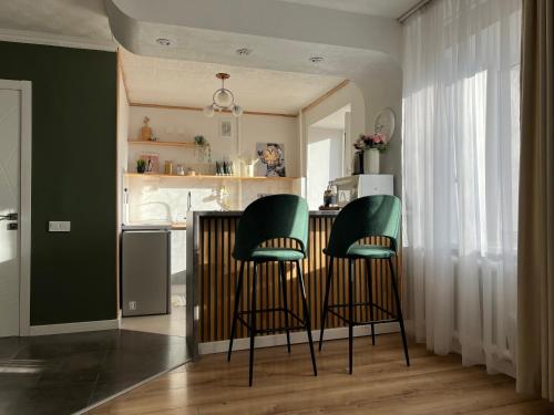 阿斯塔纳Уютная студия в скандинавском стиле в центре的酒吧的厨房配有两把绿色椅子