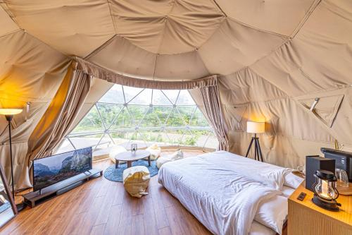 UgataTHE GLAMPING PLAZA 伊勢志摩BASE的一间卧室配有一张床,帐篷内配有电视