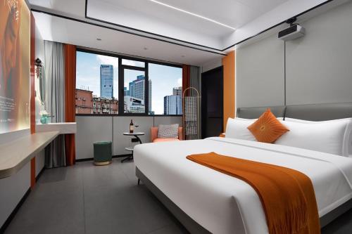 长沙沐沐酒店(长沙五一广场地铁站店)的一间带大床的卧室,享有城市美景