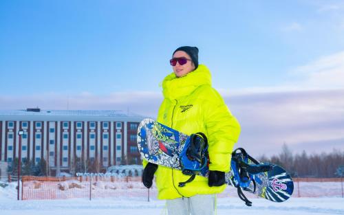 博罗沃耶博罗沃厄里克瑟斯酒店的穿着黄色夹克,拿着滑雪板的人