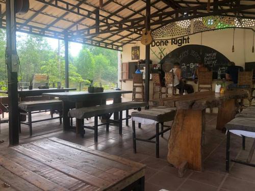 Phumĭ Chroŭy Svay‘The Greenhouse’ Nesat Village的一间餐厅,在房间内配有桌子和长凳
