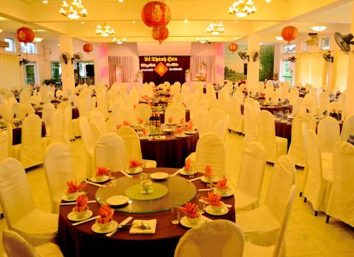 荣市Khách sạn Hữu Nghị的宴会厅配有桌子和白色椅子