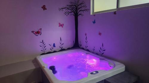 赫拉多拉Casa Mariposa的紫色浴室设有1个带树木和蝴蝶的浴缸