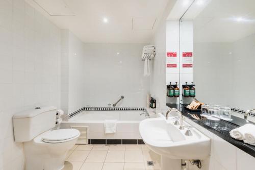 堪培拉堪培拉皇冠假日酒店的白色的浴室设有浴缸、卫生间和水槽。
