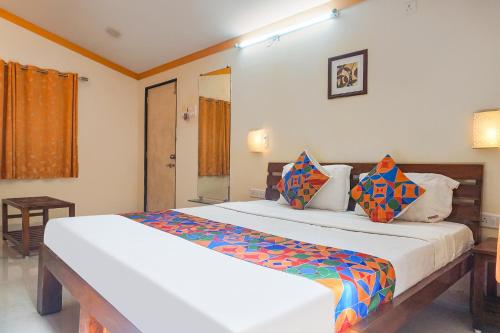 艾哈迈德讷格尔FabHotel Prime Vishwakirti Agri的卧室配有一张带彩色枕头的大型白色床。