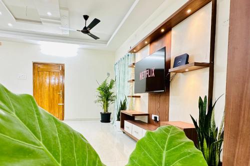 蒂鲁帕蒂TrueLife Homestays - Sai Nivas - 3BHK AC Apartments for group of families - Best location - Flyover to Alipiri gate - Walk to PS4 Veg Restaurant - Modular Kitchen - Super fast WiFi - Android TV - 250 Jio Channels - Easy access to visit all Temples的一间带电视和植物的客厅