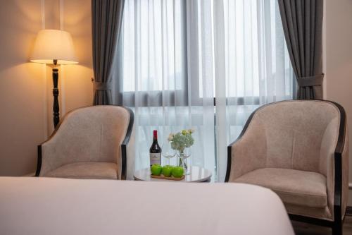 河内FTE Ba Dinh Hotel的酒店客房配有一张床、两把椅子和一张桌子
