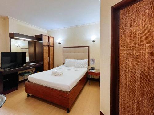 MabalacatBliss Hotel Dau的一间卧室配有一张床、一张书桌和一台电视