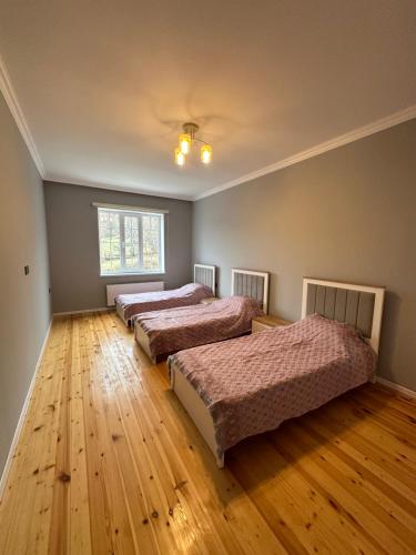 伊斯梅尔雷JLYN HOUSE的一间卧室设有三张床,铺有木地板