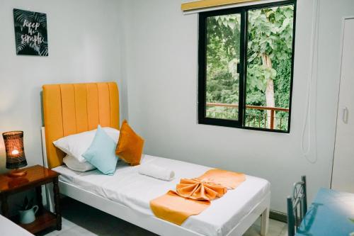 公主港Near Airport Transient Inn 2-Bedroom Space -Richkizz 1的一间卧室配有一张带橙色床头板和窗户的床。