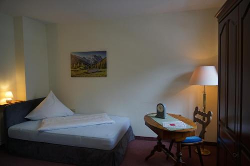 旧天鹅堡加尔尼施罗斯布里克酒店的一间卧室配有一张床和一张桌子及电话
