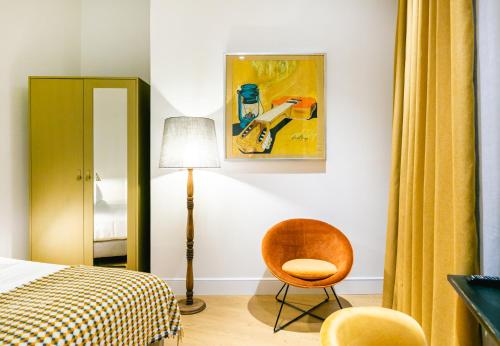 塞维利亚Joya del Casco Boutique Hotel by Shiadu的一间卧室配有一张床、一把椅子和一幅画