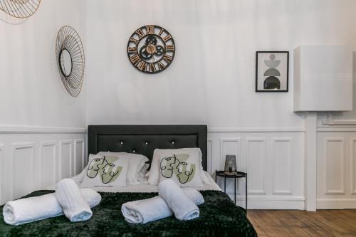 万塞讷MBA Splendide Appart - Mowat - Proche Château de Vincennes的一间卧室配有一张带白色枕头的床和时钟