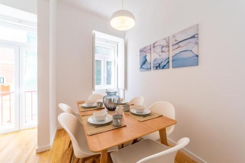 里斯本Amaro II - Sleek 2 bedroom apartment in Alcantara的一间带木桌和白色椅子的用餐室