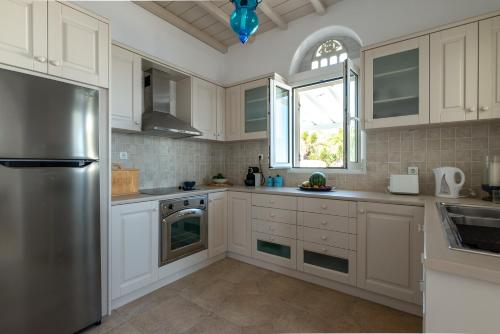 圣罗曼诺斯La Chapelle Ouest & Guest suite的厨房配有白色橱柜和不锈钢冰箱