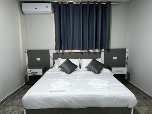 马达巴Downtown Inn Madaba的卧室配有一张带两个枕头的大白色床