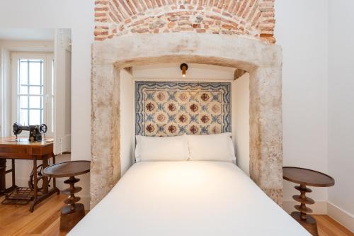 里斯本卡萨斯·拜萨 - 朱丽思和马德琳酒店的砖墙房间的一个床位